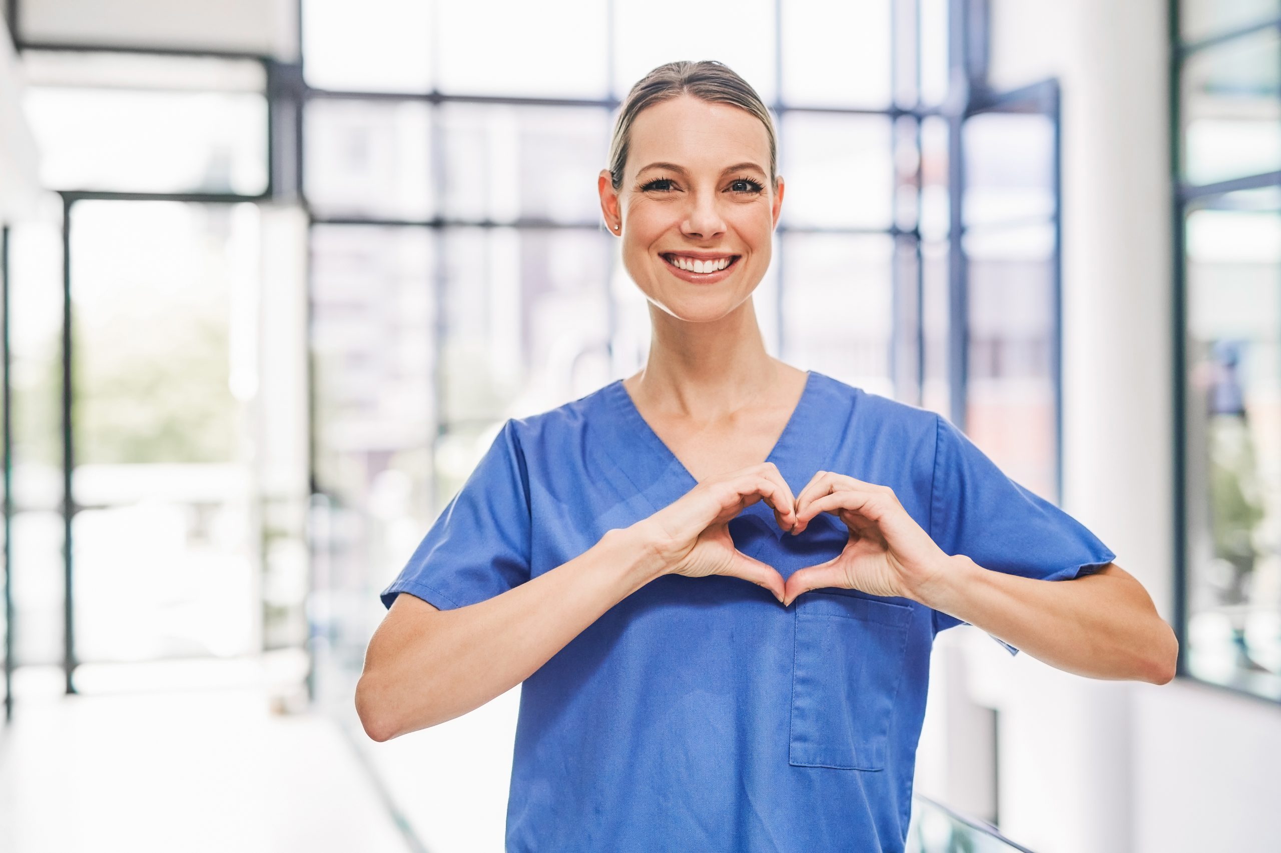 Glückliche ilomed Mitarbeiterin formt mit Ihren Händen ein Herz